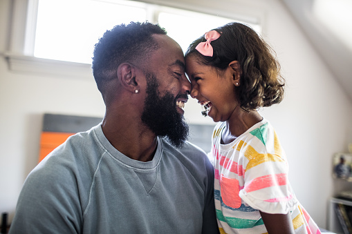 A child looks happily at an adult caregiver while he is holding
