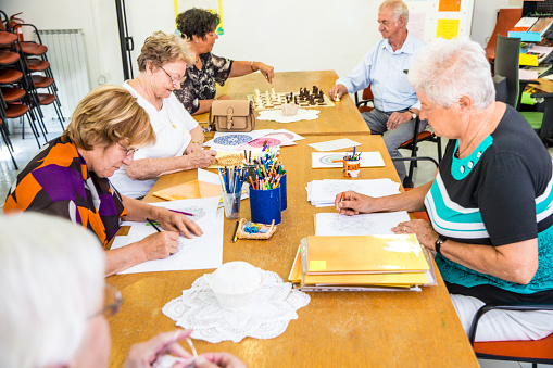 A group of adults sitting at a table together and completing an art activity.